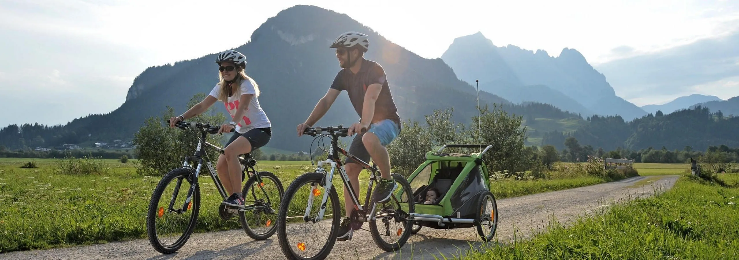 Familie beim Radfahren mit Kinderanhänger und Kleinkind in der Natur der