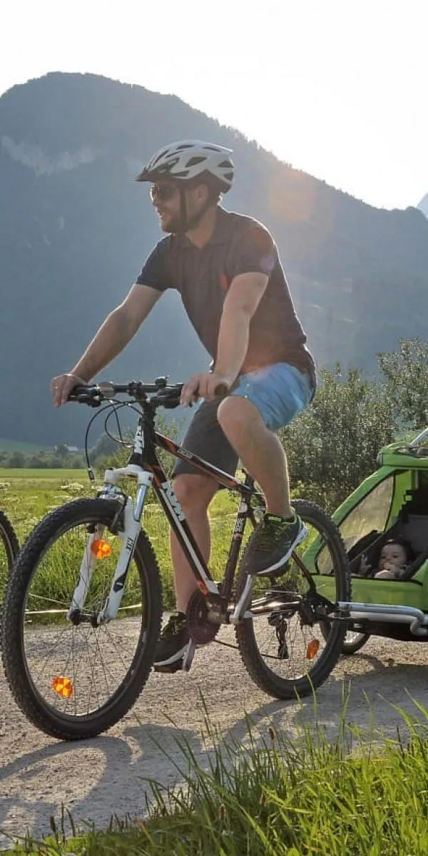 Familie beim Radfahren mit Kinderanhänger in der Landschaft der