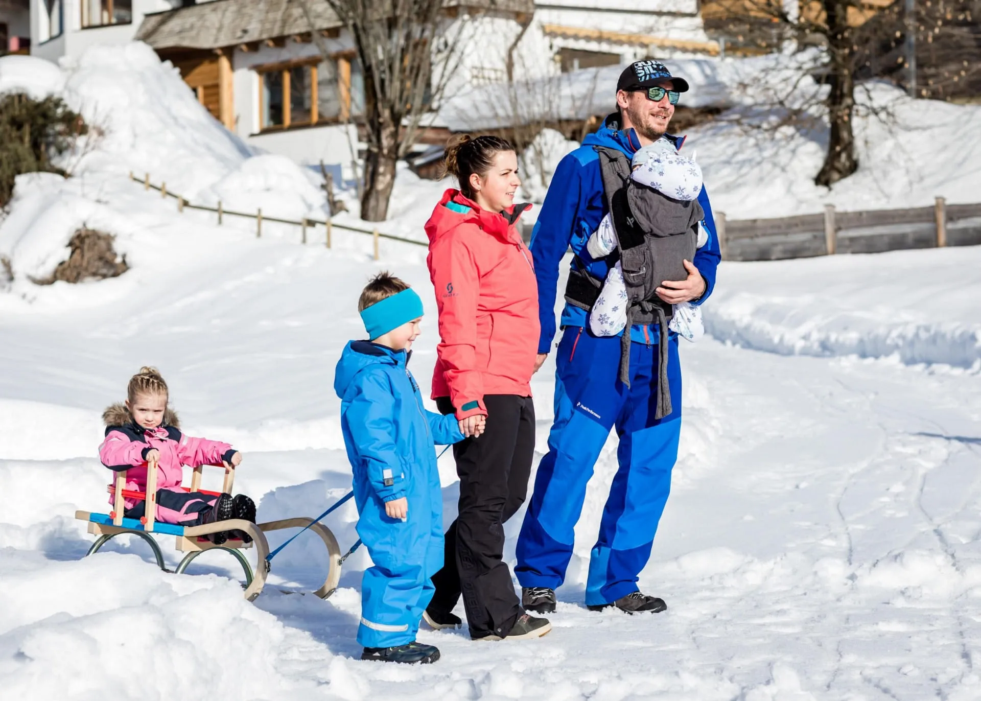 Familie mit zwei Kindern und einem Baby gehen mit Schlitten in