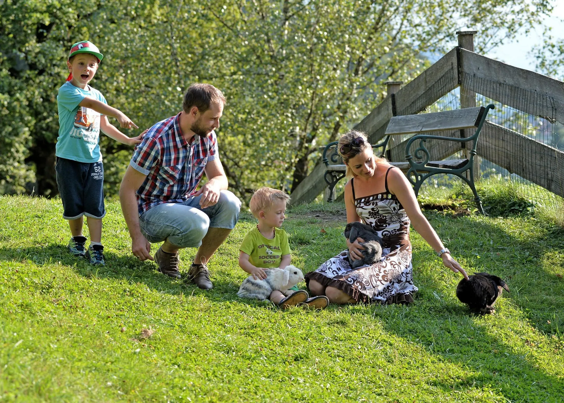 Familie mit zwei Kindern spielt mit Kaninchen und streichelt es auf einer