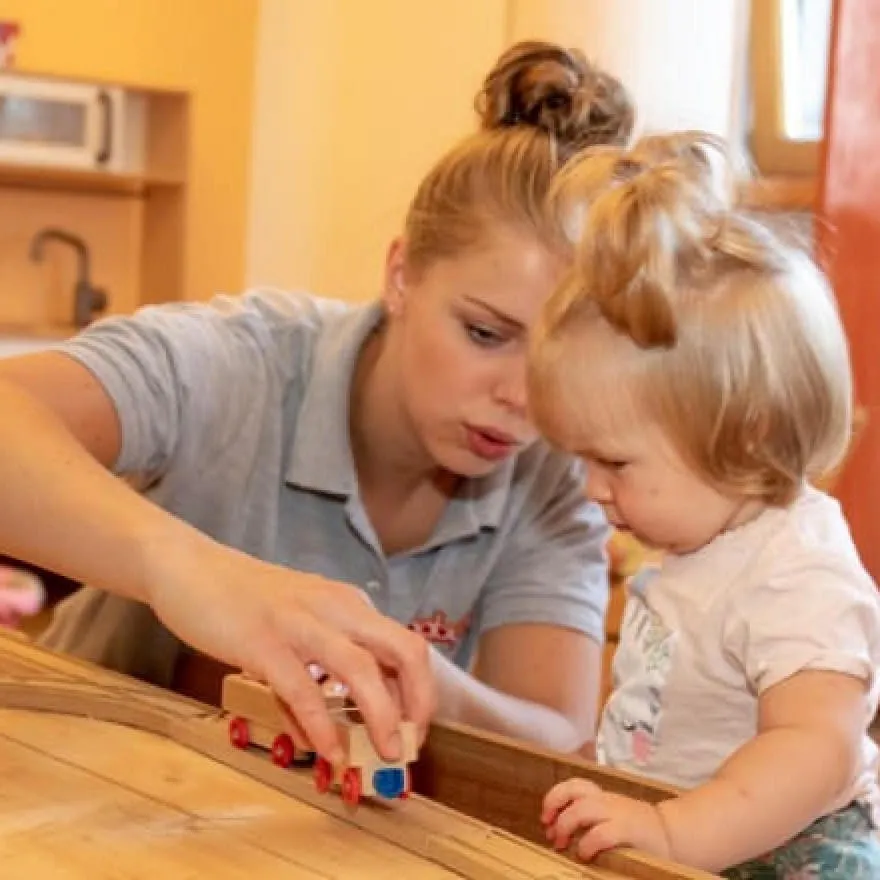 Betreuerin spielt mit Kleinkind im Baby- & Kinderhotel Babymio mit einer