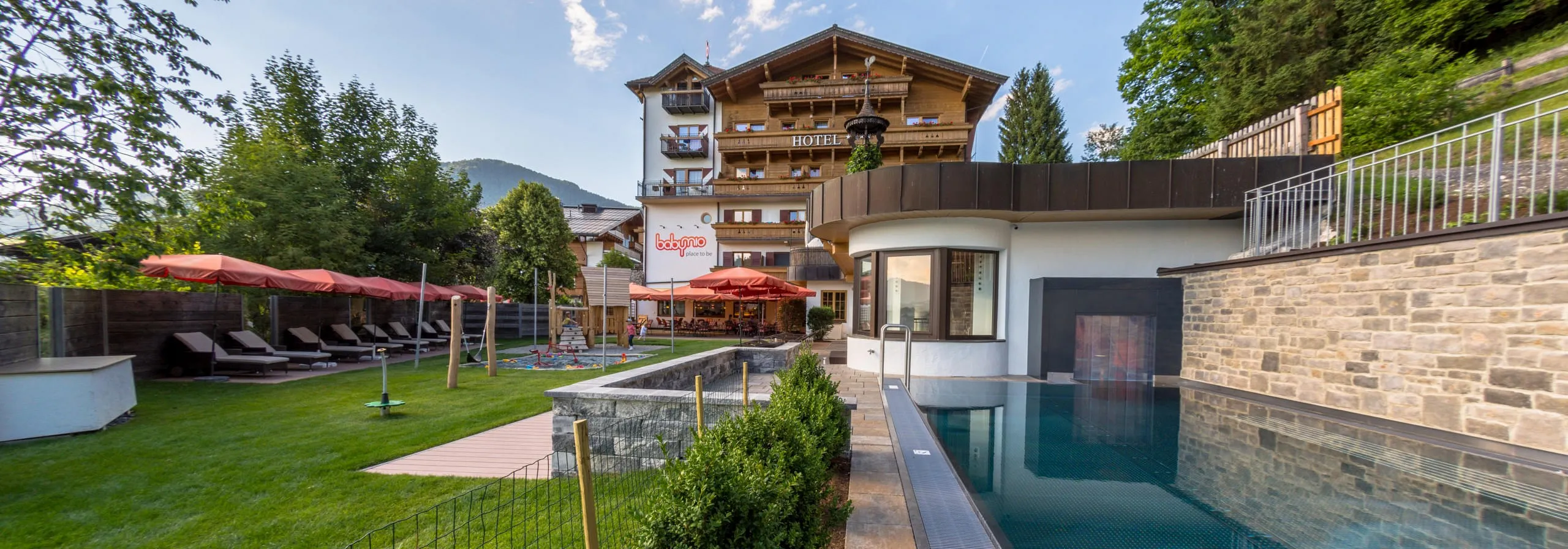 Außenansicht vom Familienhotel Babymio mit Außenpool, Gartenbereich und