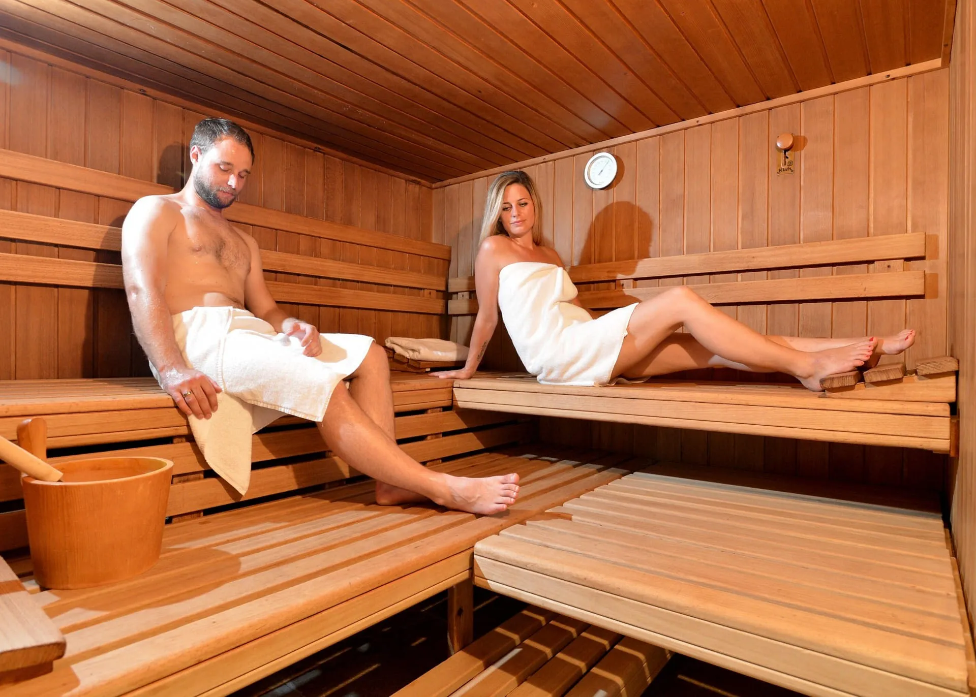 Junge Eltern - Mann und Frau entspannen in einer Holzsauna