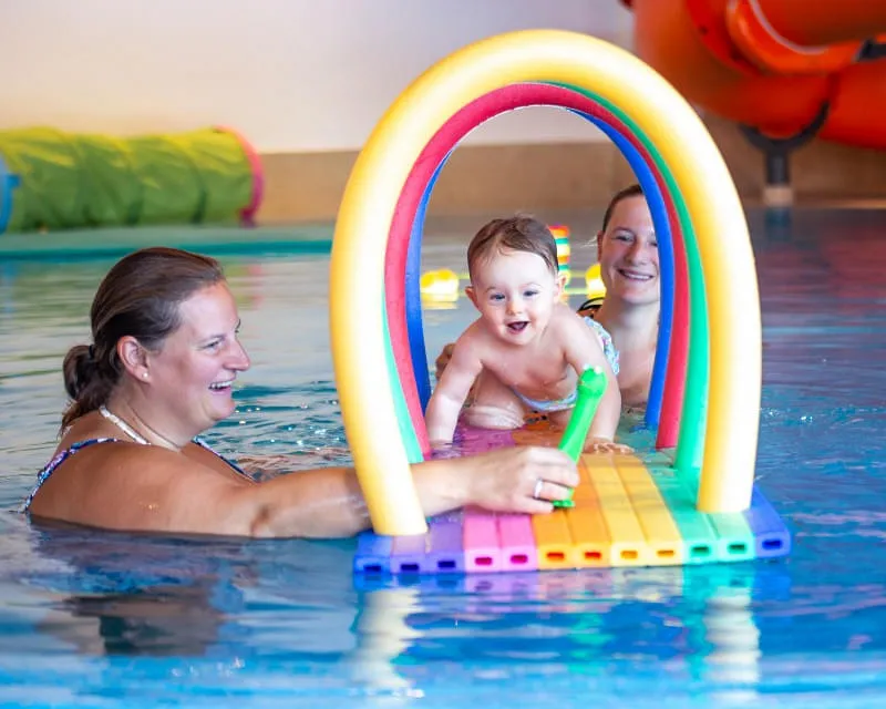 Mutter probiert Baby schwimmen zu lernen im Hallenschwimmbad des Hotel