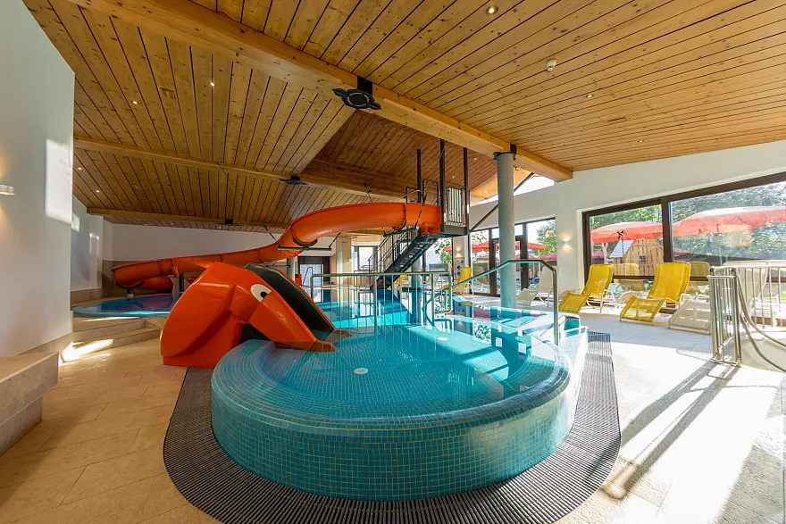 Innenansicht des Hallenschwimmbads mit Wasserrutsche und Elefantenrutsche